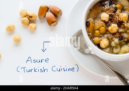 Traditionelles türkisches Gericht Asure Noah's Pudding in weißer Schüssel mit handgeschaltem Asure (türkische Küche) Löffel und Nüssen, Draufsicht Stockfoto