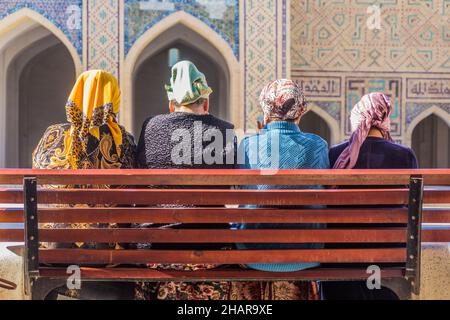 BUCHARA, USBEKISTAN - 1. MAI 2018: Einheimische Frauen sitzen auf einer Bank in der Kalyan Moschee in Buchara, Usbekistan Stockfoto