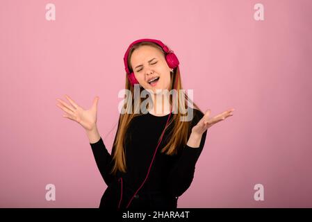 Porträt einer schönen jungen Frau mit Telefonen und leerem Schild. Kaukasisch blonde Modell posiert im Studio-Shoot, auf rosa Hintergrund. Stockfoto