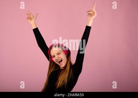 Porträt einer schönen jungen Frau mit Telefonen und leerem Schild. Kaukasisch blonde Modell posiert im Studio-Shoot, auf rosa Hintergrund. Stockfoto