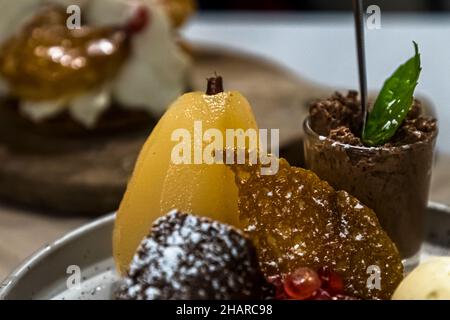 Eine pochierte Birne, ein Glas Schokoladenmousse und eine mit Puderzucker bestäubte Schokoladenkonfekt liegen neben einem Karamell-Tuile auf einem Dessertteller im Restaurant Saint Marc in Aups, Département Var, Frankreich. Stockfoto