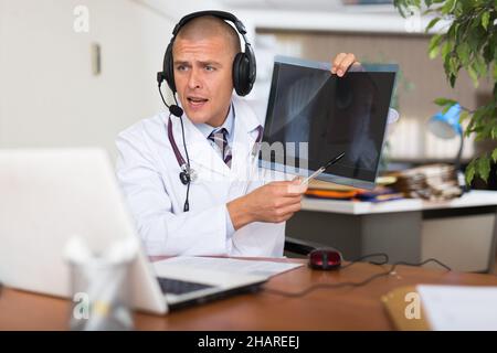 Arzt im Gespräch mit dem Patienten während der Online-Konsultation Stockfoto