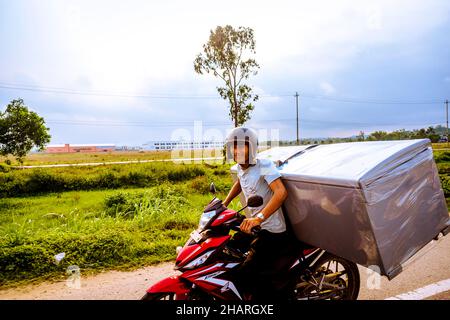 Transport eines Kühlschranks mit dem Motorrad in VN von der Vorderseite aus. Stockfoto