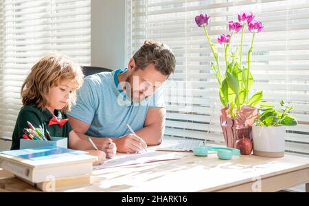 Bärtiger Vater schreibt Schulaufgaben mit seinem Sohn im Klassenzimmer, Wissen Stockfoto