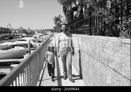 Gemeinsam spazieren gehen. Vater und Sohn gehen mit Händen auf die Promenade. Mann und Kind genießen gemächlichen Spaziergang Stockfoto