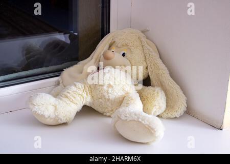 Ein weiches Spielzeug-Kaninchen liegt vergessen auf der Fensterbank Stockfoto