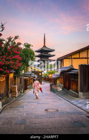 Japanisches Mädchen in Yukata mit rotem Regenschirm in der Altstadt von Kyoto, Japan Stockfoto