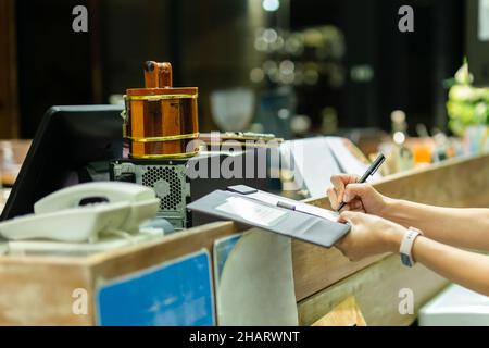 Frau in Schutzmaske Unterschriftsbelege Zahlung Kreditkarte im Restaurant. Stockfoto