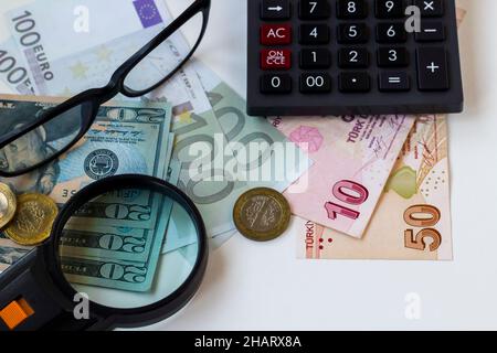 Türkische Geldscheine auf der weißen Oberfläche mit Lupe, Brille und schwarzem Taschenrechner. Stockfoto