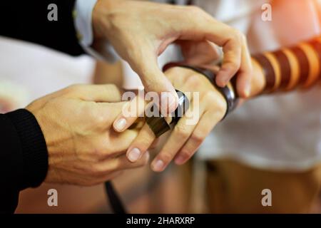 Detail eines Moments, in dem ein jüdischer Rabbiner Tefillin auf den Arm eines dreizehnjährigen Jungen legt, um vor der Bar Mizwa ein Gebet zu sprechen Stockfoto