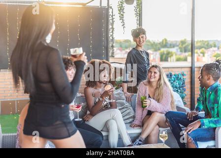 Fröhliche multiethnische Freunde auf der Terrasse, die Spaß haben und trinken Stockfoto