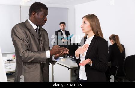 Verärgerter Mann Chef pointing zu vermissen in der Arbeit zu weiblich Stockfoto