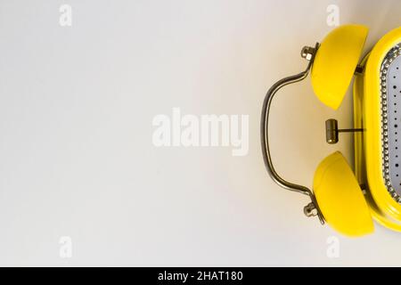 Ein gelber Retro-Wecker auf weißer Oberfläche mit großem Kopierbereich Stockfoto
