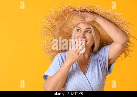 Überrascht reife Frau in Strohhut Blick beiseite auf Farbe Hintergrund Stockfoto