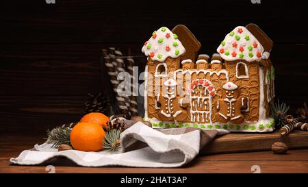 Brett mit Lebkuchenhaus und Mandarinen auf Holzhintergrund Stockfoto