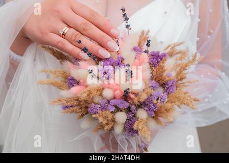 Unkrautblumen Hintergrund in den Händen. Braut hält ihren Jäten-Strauß mit trockenen Blumen. Handgefertigter Blumenstrauß. Unkrautdekorationen Stockfoto