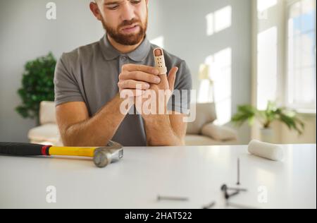 Der verletzte Mann legt nach der Arbeit mit dem Hammer zu Hause eine verstellbare Keilschiene an. Stockfoto