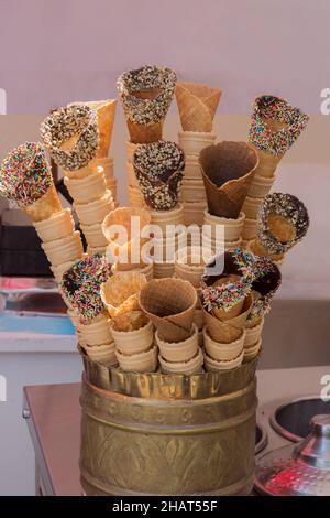 Leere Zapfen, die mit Schokolade, Haselnuss, Erdnuss und bunten Süßigkeiten bedeckt sind, Reihen sich in einer Kupferschüssel zusammen. Kein Eis Selective Focus Stockfoto