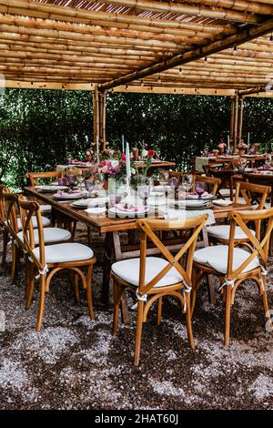 Terrasse mit Tischen mit Blumen und Tellern auf dem Tisch, die für Hochzeitsempfänge in Lateinamerika dekoriert sind Stockfoto