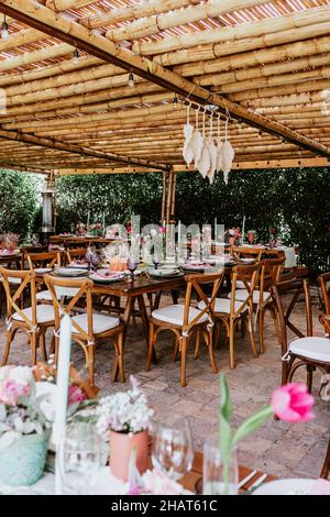 Terrasse mit Tischen mit Blumen und Tellern auf dem Tisch, die für Hochzeitsempfänge in Lateinamerika dekoriert sind Stockfoto