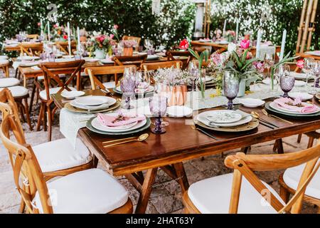 Terrasse mit Tischen mit Blumen und Tellern auf dem Tisch, die für Hochzeitsempfänge in Lateinamerika dekoriert sind Stockfoto