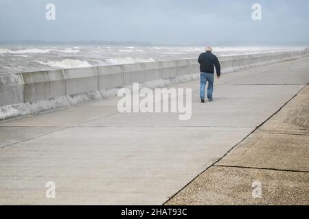 Mann, auf, Promenade, Ufer, Wellen, die, Wetter, täglich, im Freien, im Freien, Sport, Wandern, Promenade, Strandpromenade, Seeverteidigung, Seeverteidigung, Meer, Ärmelkanal, Wetter, raue Meere, wild, Bedingungen, Sturm, stürmisch, windig, Wind, Wetter, auf, Küste, Küste, Dungeness, Kent, England, Englisch, GB, Großbritannien, Großbritannien, Großbritannien, Großbritannien, Europa, Europa, Europa, Tag, August, Sommer, Sommer Stockfoto