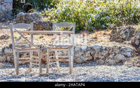 Open-Air-Café-Bar. Typische Straßencafeteria, runder Metalltisch und Holzstühle auf Kieselsteinen. Leere Plätze im Freien, sonniger Tag Stockfoto