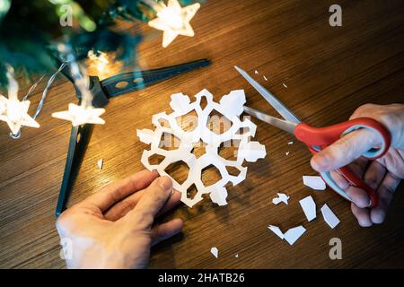 Schneiden der Schneeflockenform aus einem Papier Stockfoto