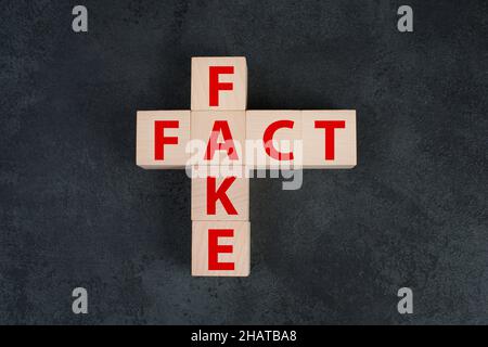 Die Worte Fact und Fake stehen auf Holzblöcken in roten Buchstaben Stockfoto