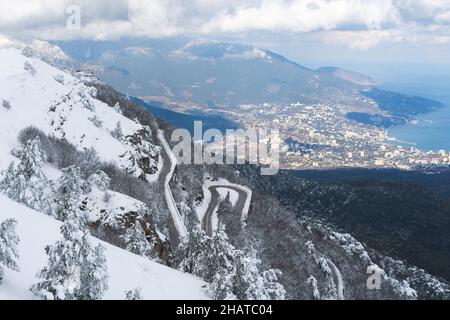 Winter Jalta Blick Ai-Petri. Berg Serpentin im Schnee. Flauschige Schneebäume. Panoramablick auf die Stadt von oben. Eine verschneite, kurvenreiche Straße. Maj Stockfoto