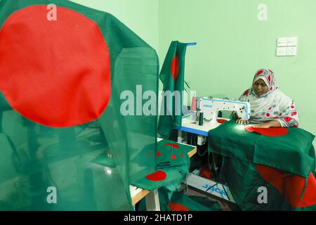 Ein Arbeiter näht die Nationalflagge von Bangladesch vor dem Siegesstag in Narayanganj, am Stadtrand von Dhaka, Bangladesch, am 14. Dezember 2021. Am 16. Dezember wurde zum Gedenken an den Sieg der Streitkräfte Bangladeschs über die pakistanischen Streitkräfte im Befreiungskrieg von Bangladesch im Jahr 1971 ein Siegestag gefeiert. Der Kommandeur der pakistanischen Streitkräfte, General AAK Niazi, gab sich mit seinen Truppen den alliierten Kräften von Bangladesch hin, was das Ende des 9 Monate andauernden Bangladesh Liberation war und 1971 den Völkermord in Bangladesch und die offizielle Abspaltung Ostpakistans nach Bangladesch bedeutete. Foto von S Stockfoto