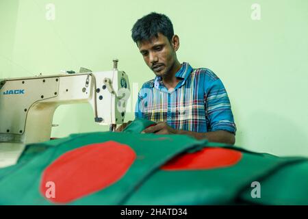 Ein Arbeiter näht die Nationalflagge von Bangladesch vor dem Siegesstag in Narayanganj, am Stadtrand von Dhaka, Bangladesch, am 14. Dezember 2021. Am 16. Dezember wurde zum Gedenken an den Sieg der Streitkräfte Bangladeschs über die pakistanischen Streitkräfte im Befreiungskrieg von Bangladesch im Jahr 1971 ein Siegestag gefeiert. Der Kommandeur der pakistanischen Streitkräfte, General AAK Niazi, gab sich mit seinen Truppen den alliierten Kräften von Bangladesch hin, was das Ende des 9 Monate andauernden Bangladesh Liberation war und 1971 den Völkermord in Bangladesch und die offizielle Abspaltung Ostpakistans nach Bangladesch bedeutete. Foto von S Stockfoto