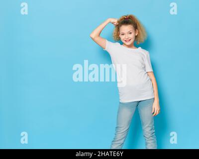 Fröhliches Mädchen mit lockigen Haaren in einem weißen Hemd Emotionen blauen Hintergrund Stockfoto