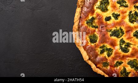 Hausgemachter Quiche-Kuchen mit Brokkoli, Thunfisch und Käse auf schwarzem Graphit-Hintergrund. Panoramaansicht, Kopierbereich Stockfoto