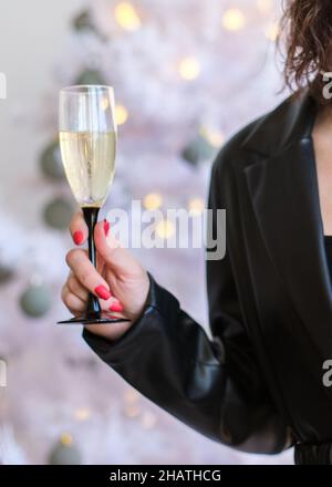 Frau feiert Neujahr mit einem Glas Champagner in der Hand, Nahaufnahme Stockfoto