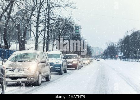 Landschaftlich schöne Aussicht Verkehr Stadt Stau an der Kreuzung Schmutz Schnee bedeckt rutschige Straße fahren langsam fahrende Autos stecken. Schneefall Gefahr Schneesturm Schlechtes Winterwetter Stockfoto