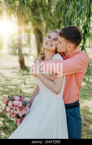 Braut und Bräutigam am Hochzeitstag zu Fuß im Freien auf Frühling Natur. Brautpaar, gerne frisch verheiratete Frau und Mann umarmen im Green Park. Liebe Hochzeit Stockfoto
