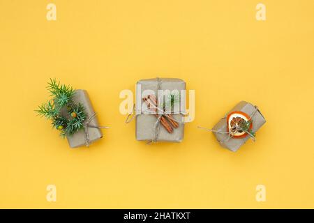 Zero Waste Weihnachtskonzept. Natürliche Geschenkmaterialien Papier Tannenzweige getrockneter Zitruszimon auf gelbem Hintergrund. Flache Ansicht von oben. Öko-Greeti Stockfoto