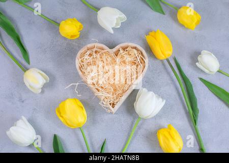 Leere Geschenk Holzkiste in Form eines Herzens für Öko-Geschenk mit dekorativem zerkleinerten Papier um Tulpen Blumen gefüllt. Modell. Gratulation Konzept Stockfoto