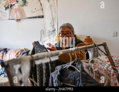 (211215) -- LHASA, 15. Dezember 2021 (Xinhua) -- Tsering Drolma arrangiert ihre Kleidung in ihrem Haus in Lhasa, südwestlich der Autonomen Region Tibet, am 7. Dezember 2021. Tsering Drolma, geboren 1940, ist Rentner und lebt im Stadtgebiet von Lhasa. Sie war einst Leibeigene und führte in ihrer Kindheit ein elendes Leben. Im Alter von 8 Jahren war sie zu jung, um schwere Arbeit zu verrichten, so dass sie vom Leibeigenen nur wenige Rationen verdienen konnte. Abgesehen von dem Hungertod musste sie die Kälte ertragen, als ihr Leibeigenbesitzer nachts draußen mit Vieh schlief. „Was für ein Glück war es, jeden Tag etwas früher in der Sonne zu baden. Stockfoto