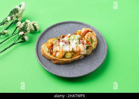 Toast mit Garnelen, Garnelen, Avocado und pochiertem Ei auf grünem Hintergrund mit Blumen Stockfoto