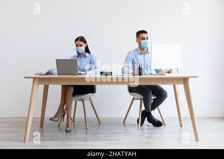 Kollegen in Einweg-Gesichtsmasken arbeiten am pc im Büro Stockfoto