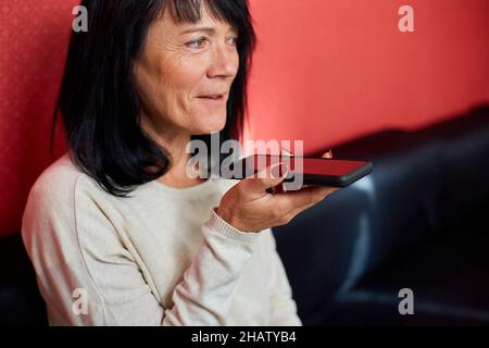 Reife Geschäftsfrau Freiberufler nehmen Audio-Nachricht auf Smartphone, diktieren Sprachnachricht an Kunden, Mitarbeiter sprechen auf Freisprecheinrichtung Telefon, verwenden Digita Stockfoto