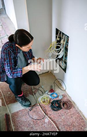 Technikerin mit Schraubendreher und Klemmenleiste zur Installation des Telekommunikationskastens Stockfoto