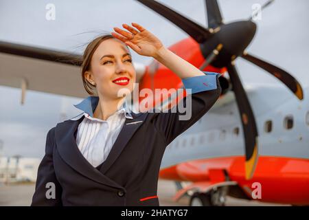 Fröhliche Frau, die im Freien am Flughafen steht Stockfoto