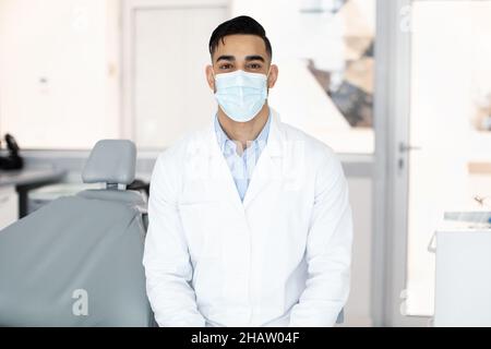 Dentalarbeiter. Porträt Eines Jungen Arabischen Männlichen Zahnarztes In Schützender Medizinischer Maske Stockfoto