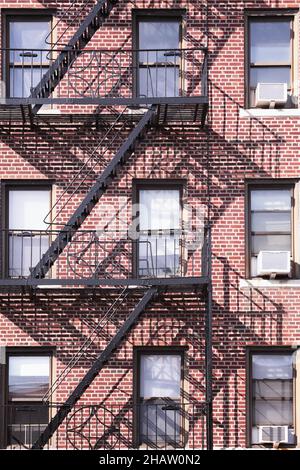 Bronx-Gebäude aus rotem Backstein mit schwarzer Feuerschutzanlage aus Metall und Schattenhintergrund Stockfoto