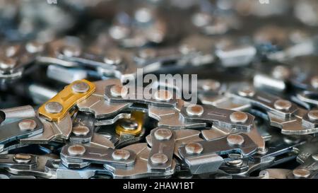 Verworrene Kettensägenstruktur mit wunderschönem unscharfem Hintergrund und Bokeh. Nahaufnahme von scharfen Stahlzähnen an Gliedern von Metallketten. Professionelles Werkzeug. Stockfoto