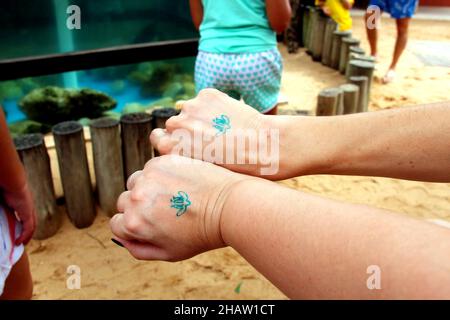 Tamar Project: Parkeingang, waschbares, ökologisches Tattoo auf der Rückseite zweier weiblicher Hände. Praia do Forte, Mata de São João - Bahia. Juli 2013. Stockfoto