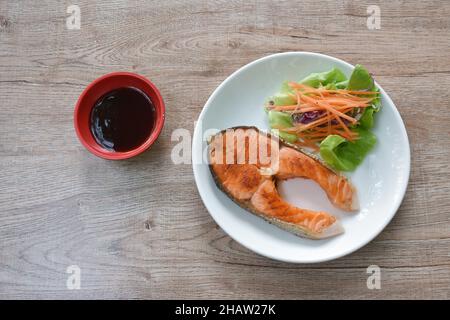 Gegrilltes Lachssteak mit Teriyaki-Sauce und frischem Gemüsesalat auf dem Teller Stockfoto
